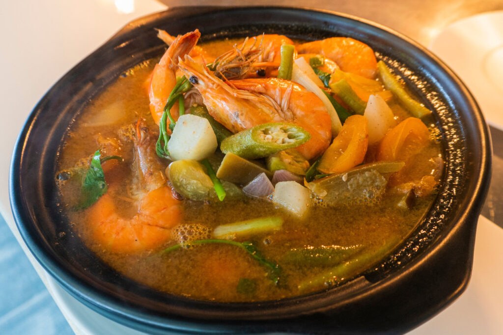 A steaming bowl of prawn sinigang with fresh vegetables in a rich, tangy broth served at Atmosphere Resorts & Spa.