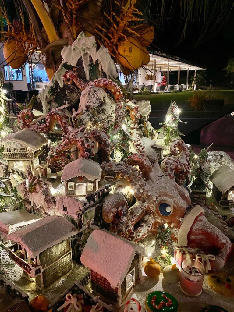 A festive gingerbread village display with glowing lights, snowy rooftops, and whimsical holiday details at Atmosphere Resorts & Spa.