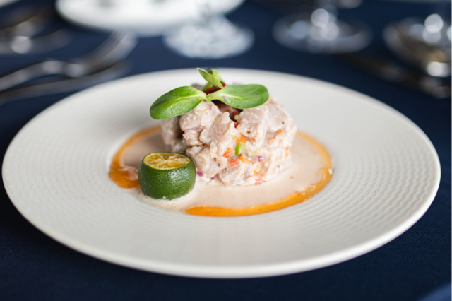 A plated serving of Filipino kinilaw made with fresh seafood, calamansi, and creamy dressing, garnished with microgreens and served in a fine dining setting.