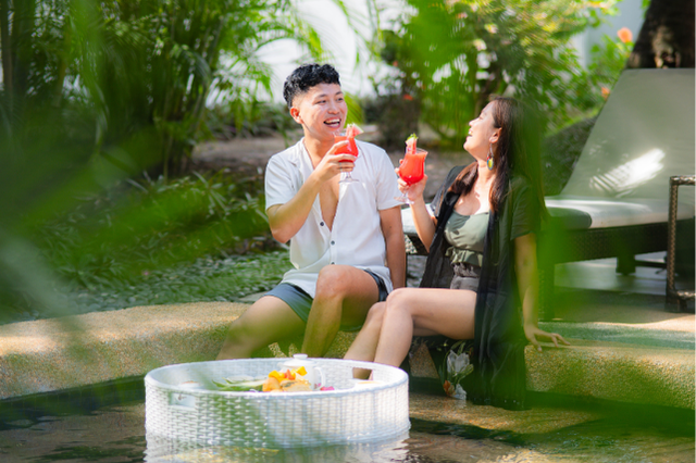 A couple relaxes beside a private pool at Atmosphere Resorts & Spa, enjoying tropical drinks and a floating breakfast surrounded by lush gardens.