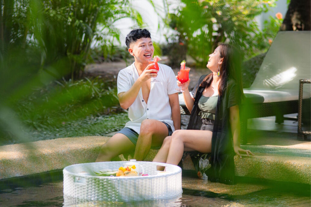 Guests relax beside a private pool at Atmosphere Resorts & Spa, enjoying tropical drinks and a floating breakfast surrounded by lush gardens.