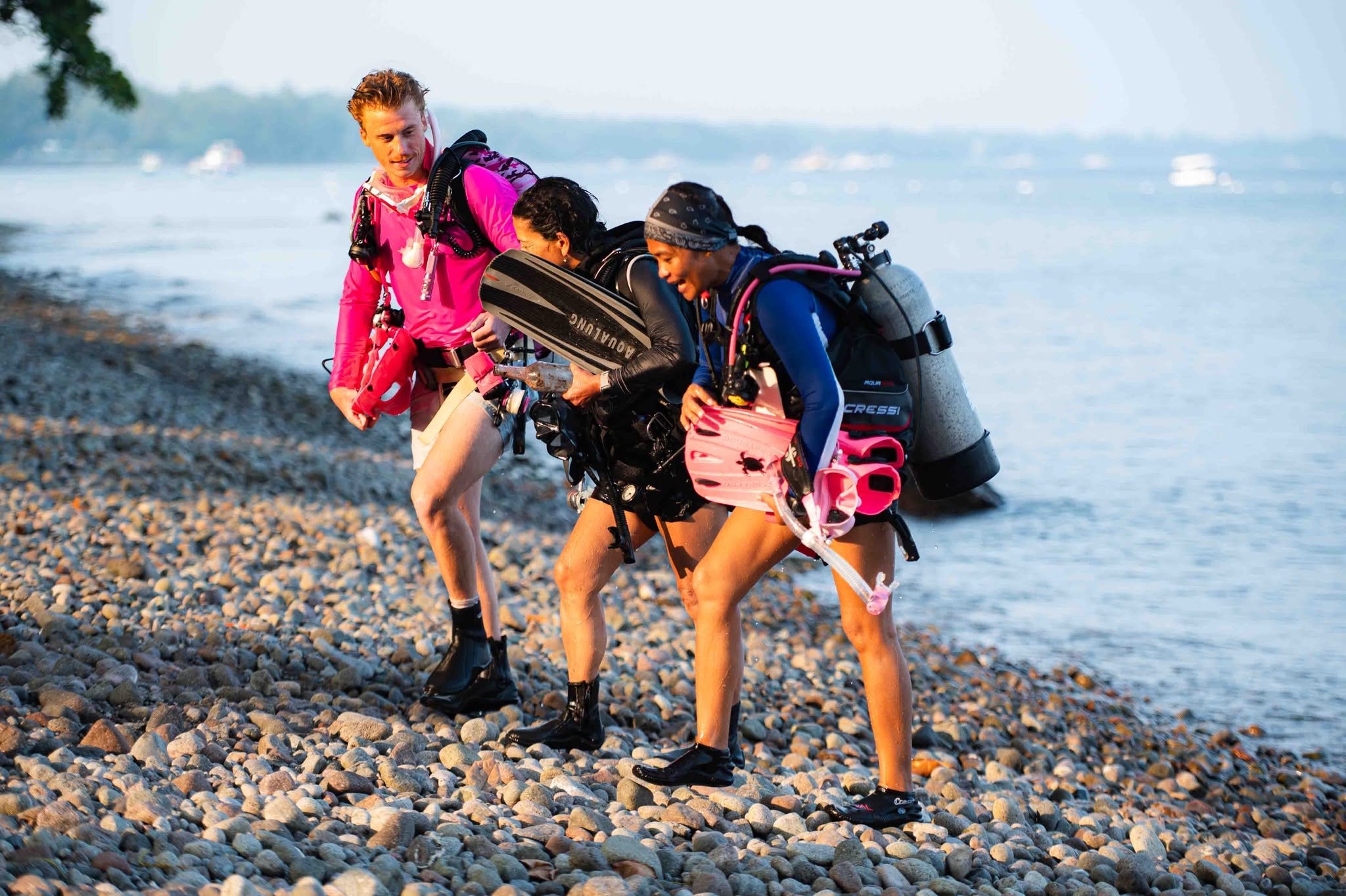 PADI Instructor Development Course students in scuba gear walking along the rocky shoreline at Atmosphere Resorts & Spa