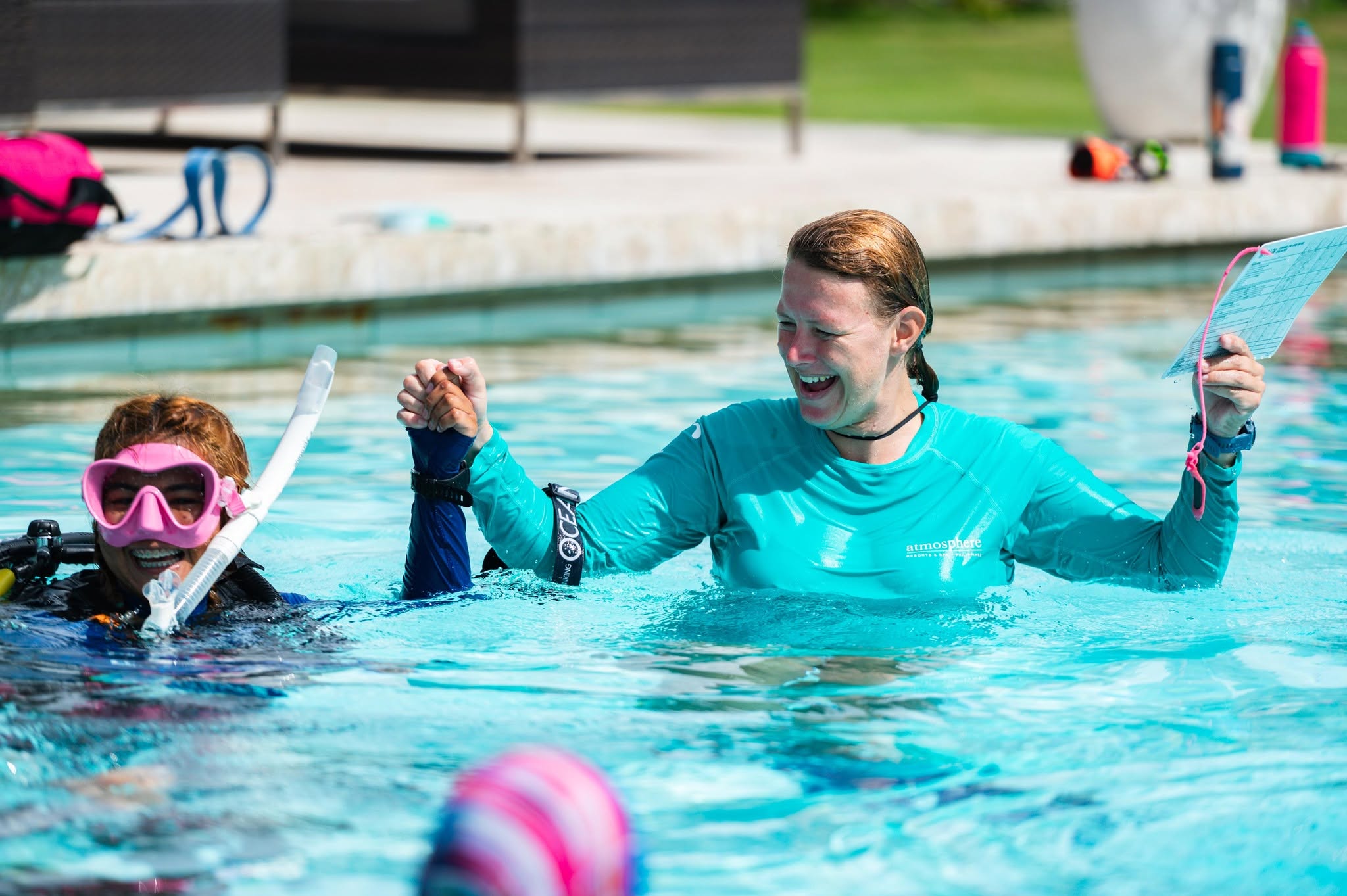 PADI Course Director Berlinda celebrating with a student during pool training at Atmosphere Resorts & Spa